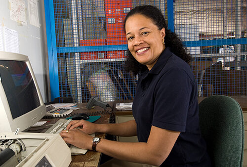 Smiling woman sitting at computer in office Smiling woman sitting at computer in office