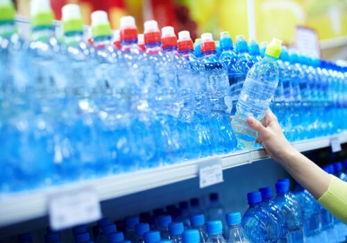 close-up-of-female-choosing-good-mineral-water-in-a-shop-SBI-325331472-min